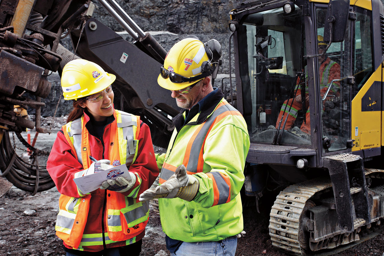 Man and Woman  reviewing details wearing saftey gear